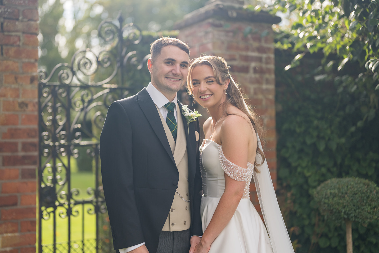 Ailsa and Matt smiling together at the garden gates at Colshaw Hall