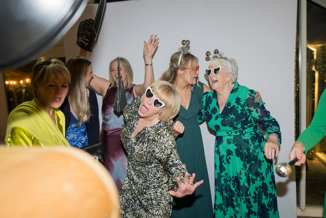 Guests laughing and wearing heart-shaped sunglasses at the photo booth