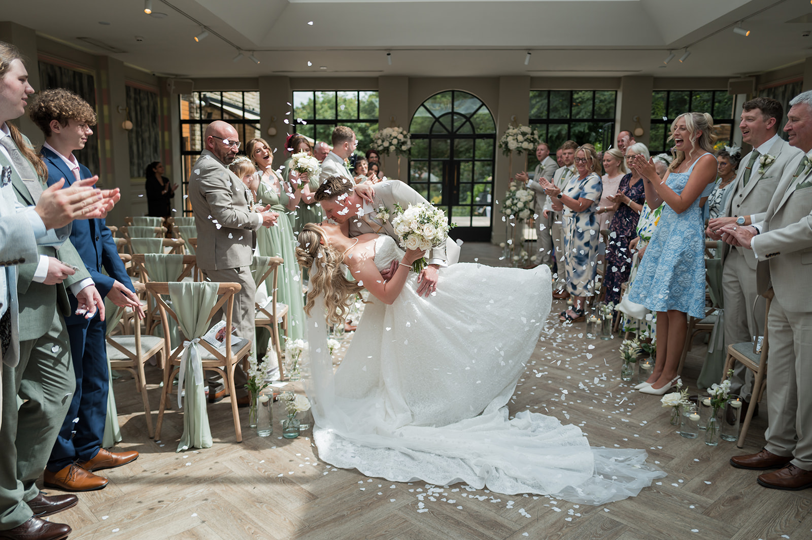 Chloe and James kissing as their guests celebrate after the ceremony at Woodlands Hotel