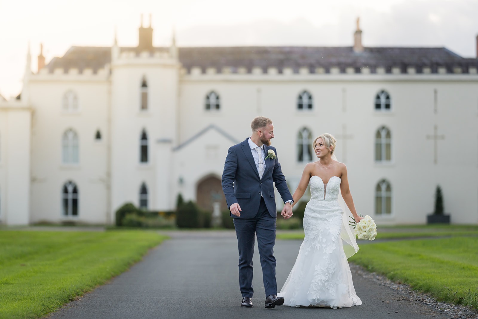 Wedding couple walking in front of the historic house at Combermere Abbey