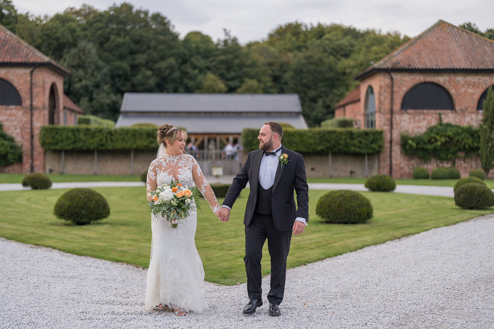 Emma and Sam walking through the courtyard between Hazel Gap Barn’s red-brick buildings