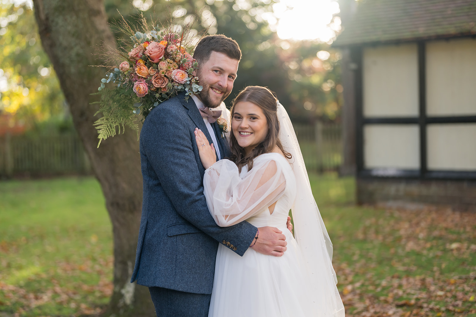 Gemma and James embracing beneath a tree in Abbeywood Estate’s autumn gardens