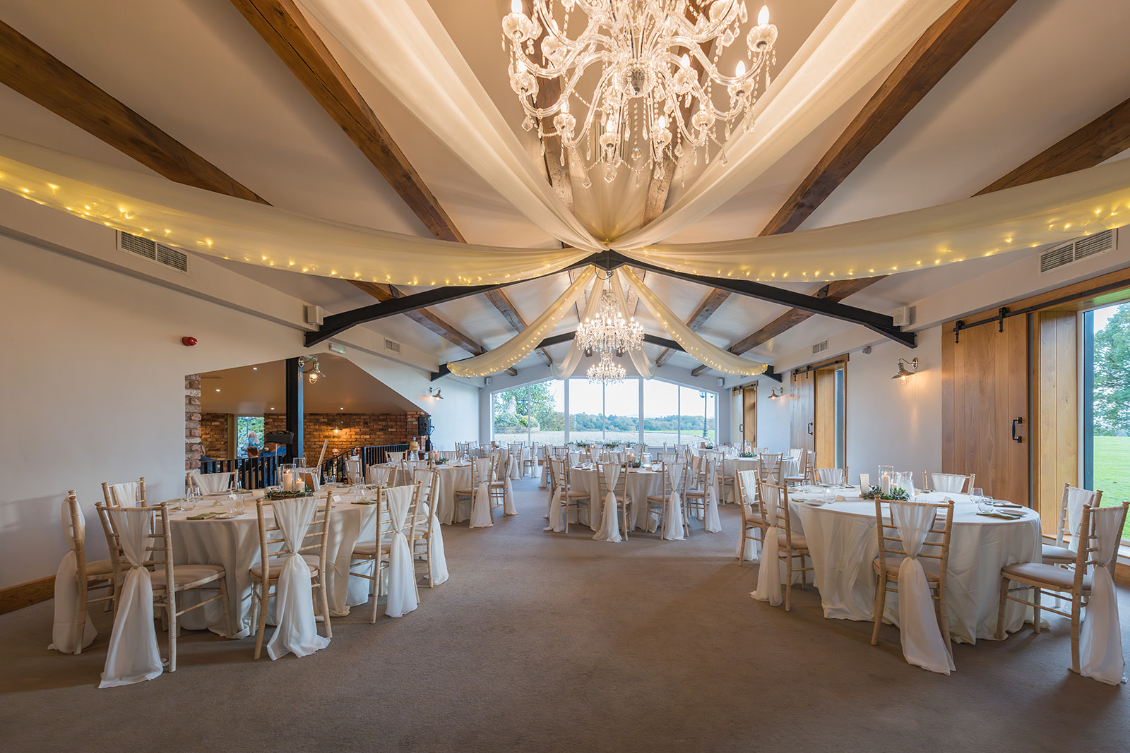 Hyde Bank Farm reception room set for a wedding breakfast with chandeliers and draped fabric