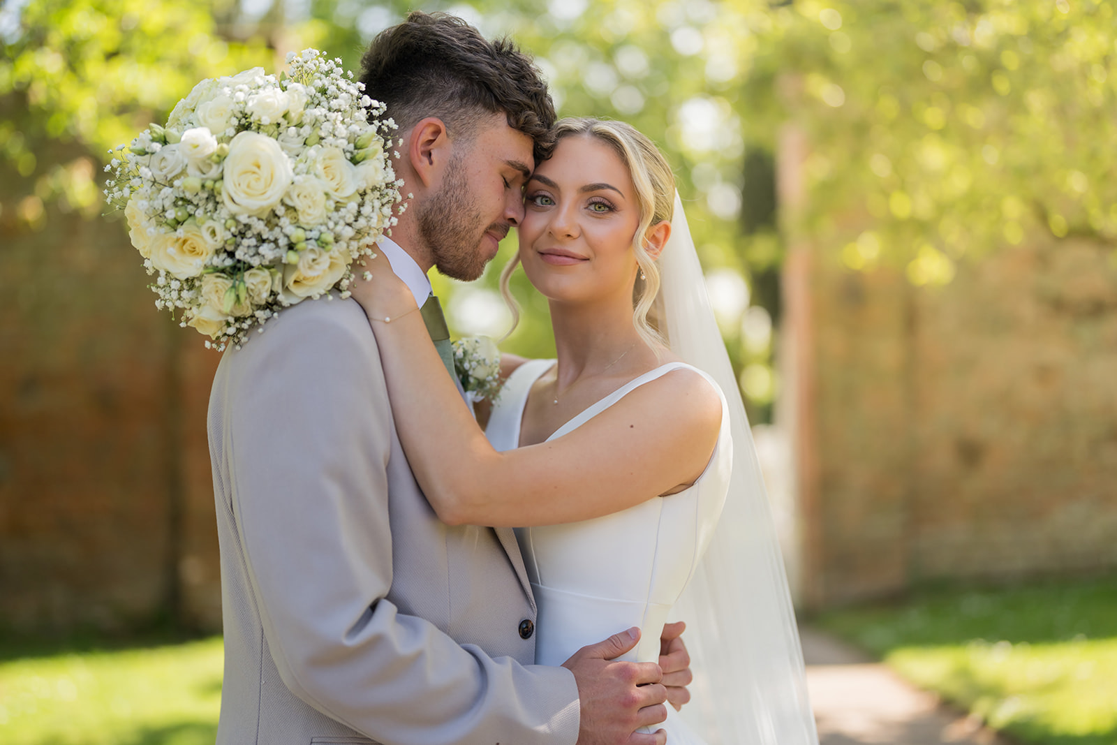 Jordan and Ben embracing among the spring greenery at Combermere Abbey