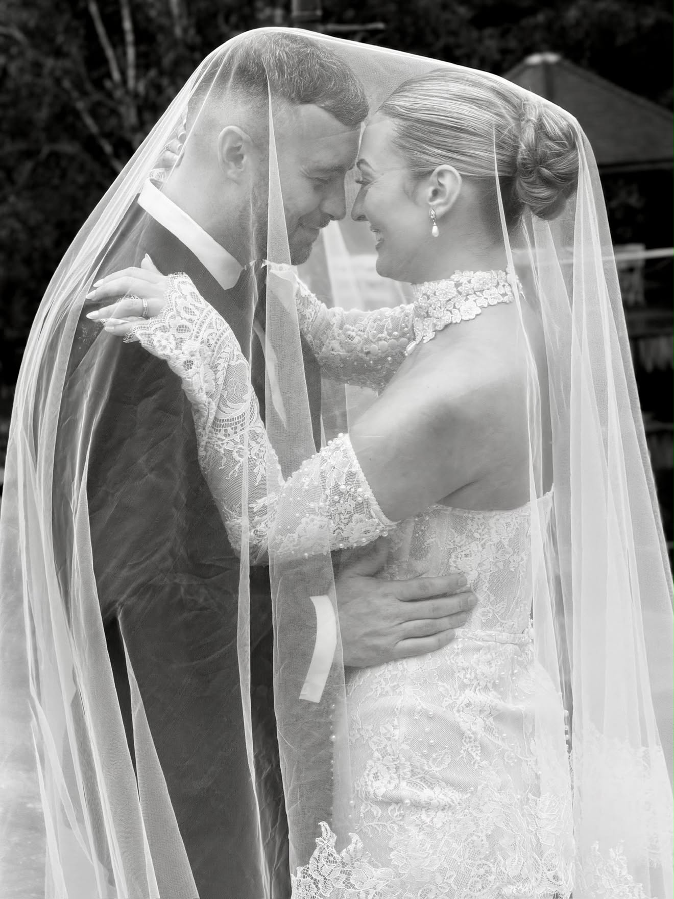 Black-and-white photograph of newlyweds together beneath a veil, supplied by Simply Socials