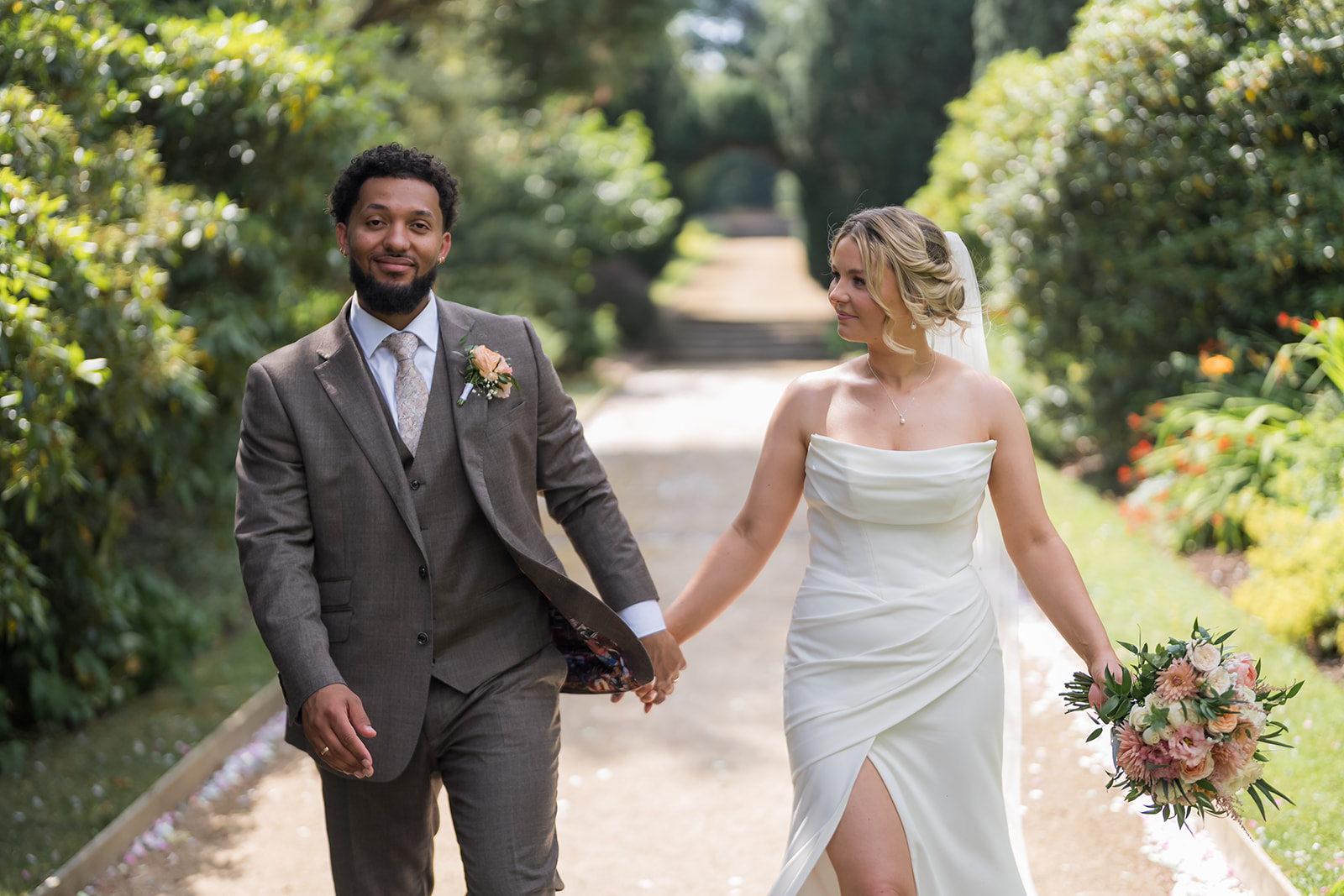 Kate and Jacob walking hand in hand through the gardens at The Orangery at Ingestre
