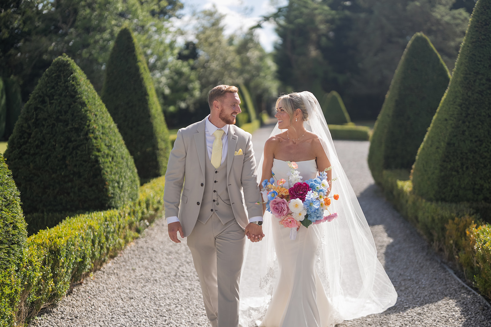 Lauren and Ryan walking hand in hand through the gardens at The River Barn