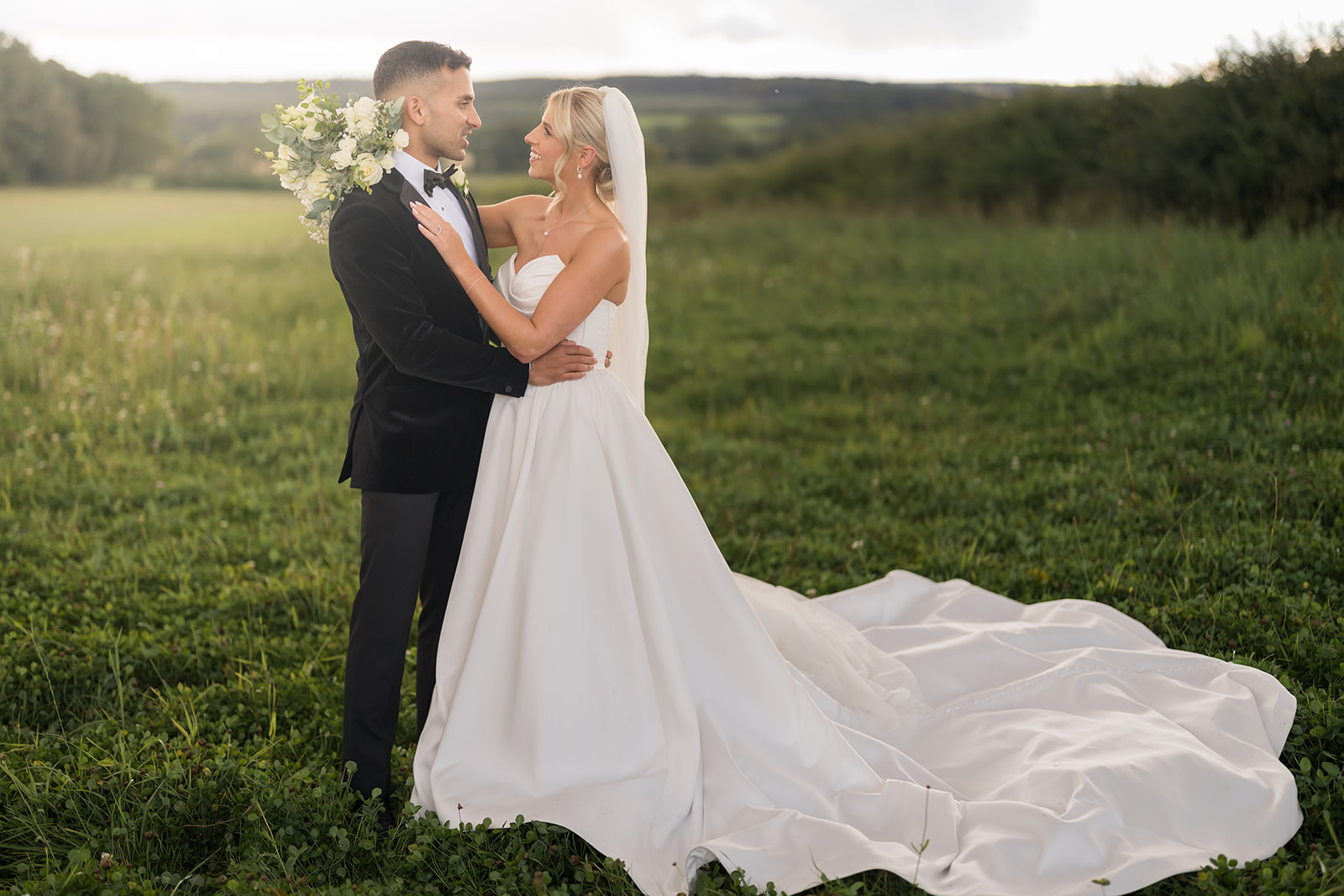 Mia and Herman embracing in a meadow with Northumberland countryside behind them