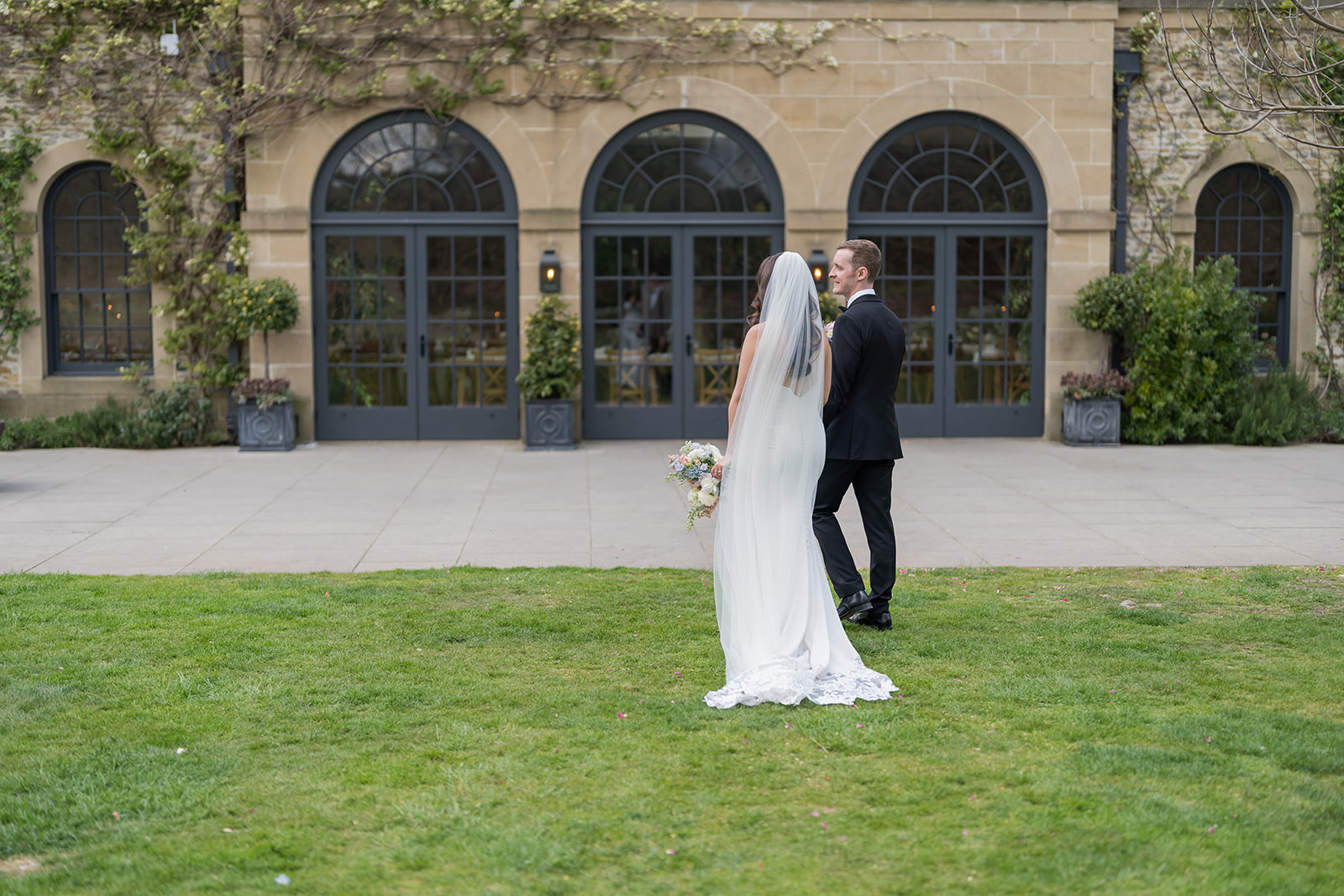 Becky and Alex on the lawn in front of Middleton Lodge’s arched garden windows