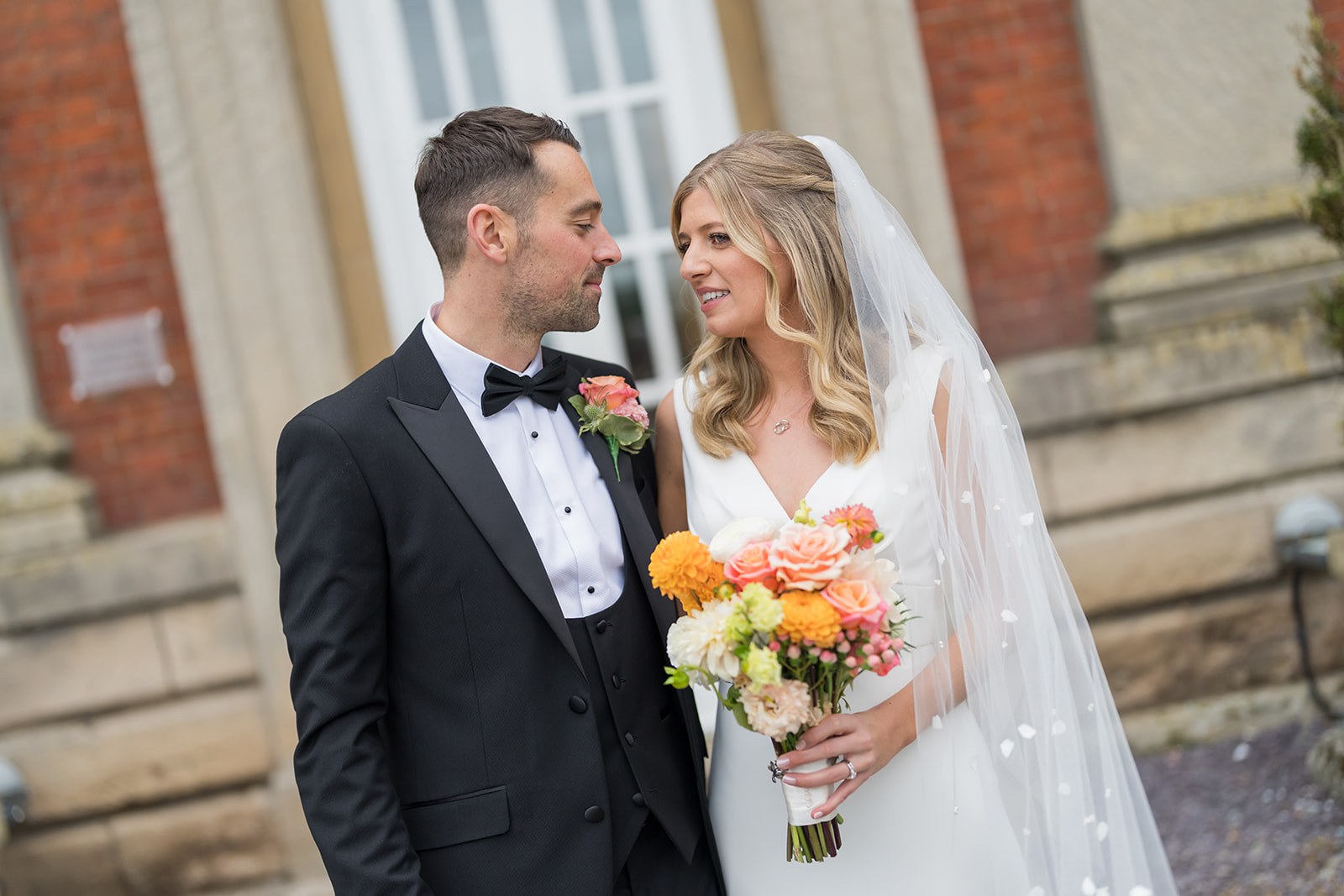 Amy and Daniel beside the red-brick frontage at Mottram Hall