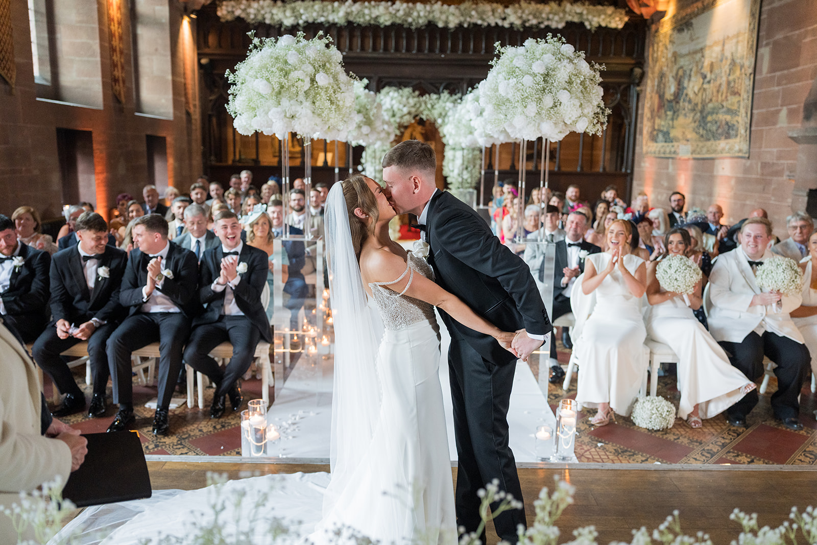 Bride and groom kissing during their ceremony in the Great Hall at Peckforton Castle