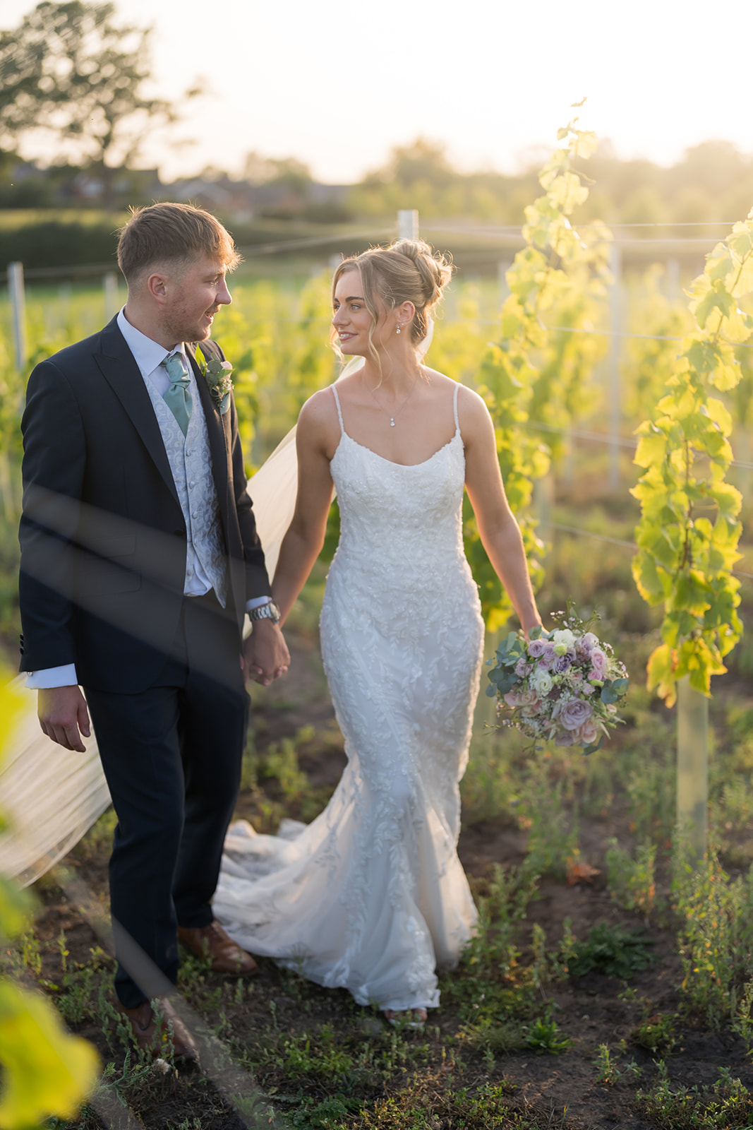 Bride and groom walking through sunlit gardens