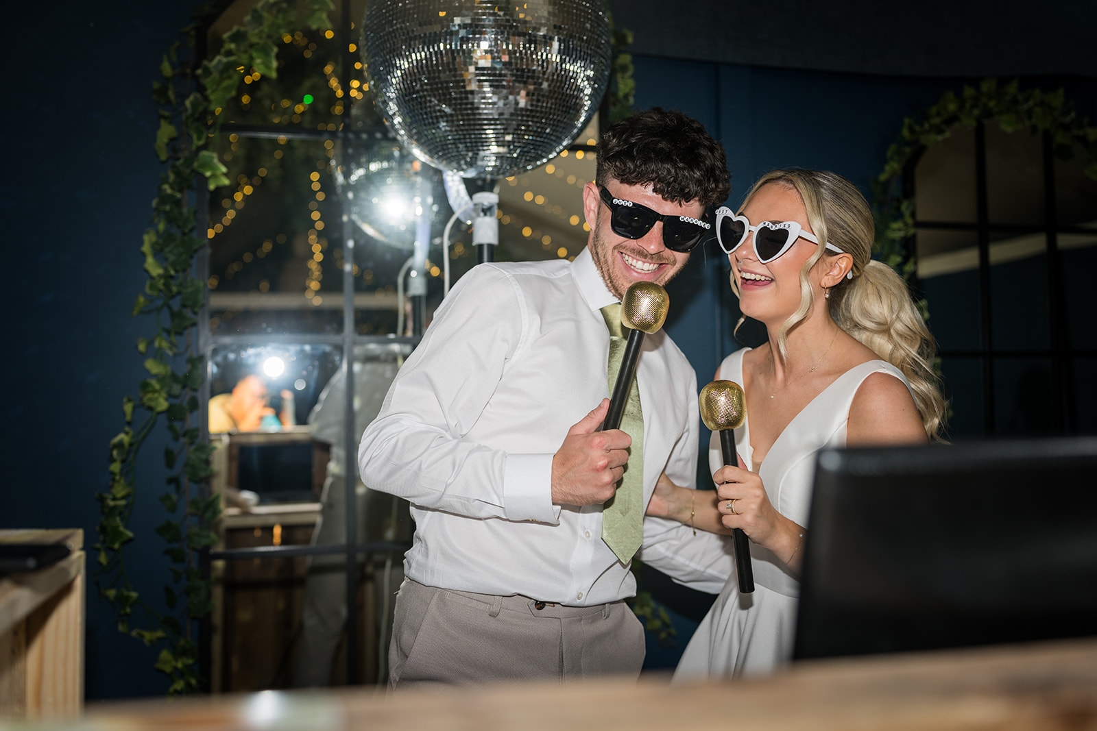 Newlyweds in sunglasses holding telephone handsets at their reception