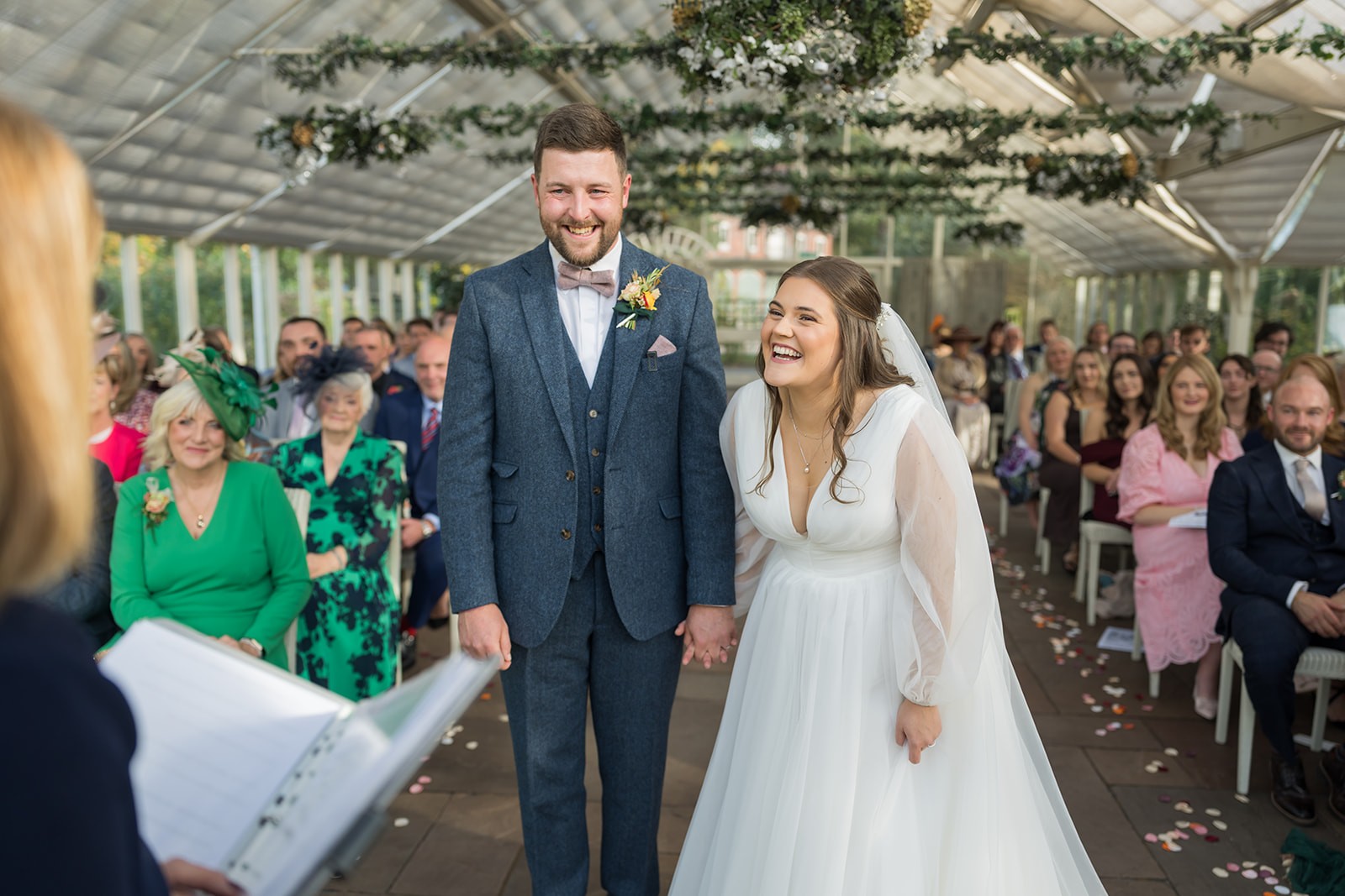 Bride and groom holding hands in front of their wedding guests