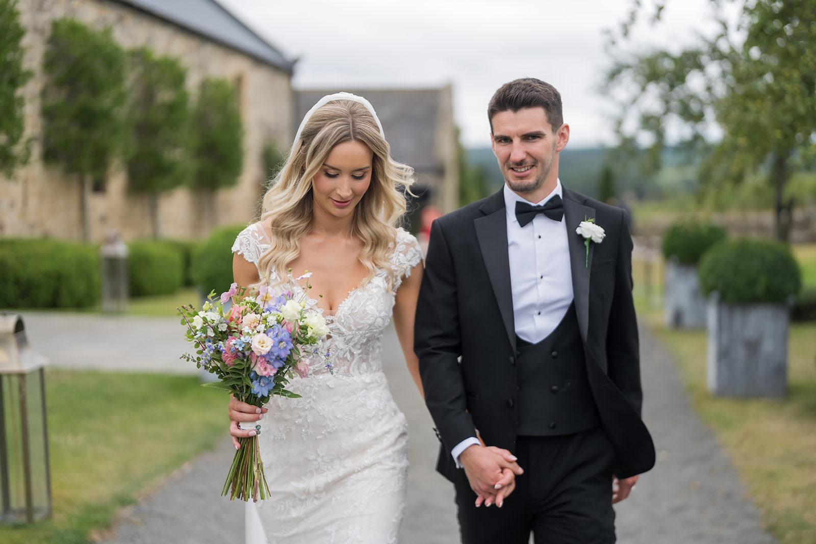Sophie and Sam walking hand in hand outside Healey Barn in Northumberland