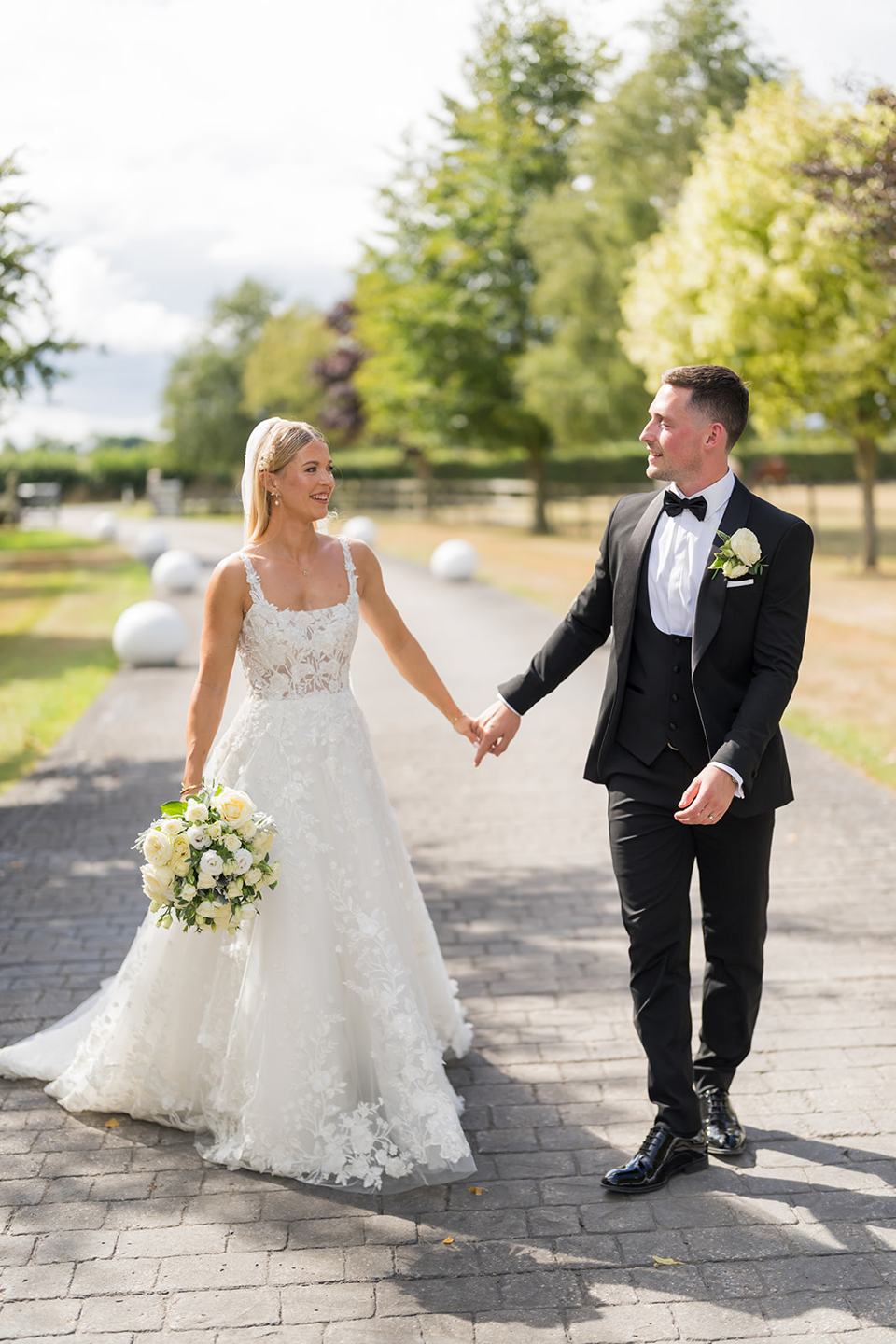 Newlyweds walking through the grounds at Evie and Josh’s Burlton Manor wedding