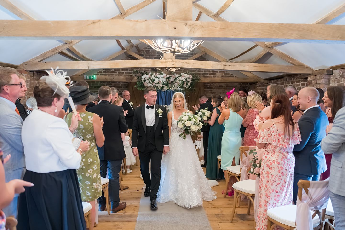 Newlyweds leaving the ceremony at Evie and Josh’s Burlton Manor wedding