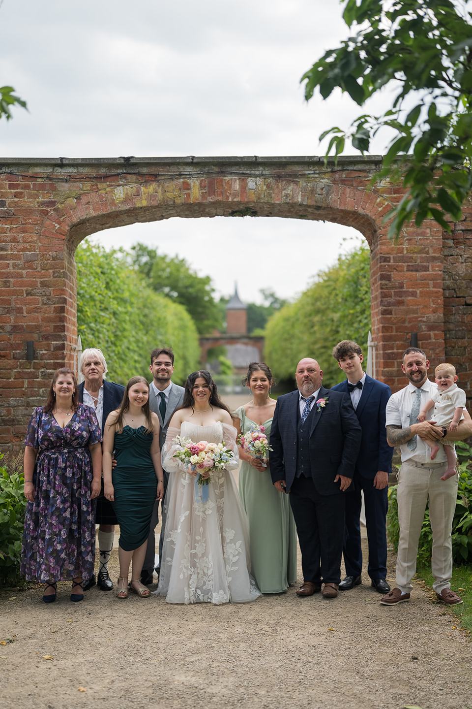 Family photographs beneath the brick arch at Abi and Ben’s Combermere Abbey wedding