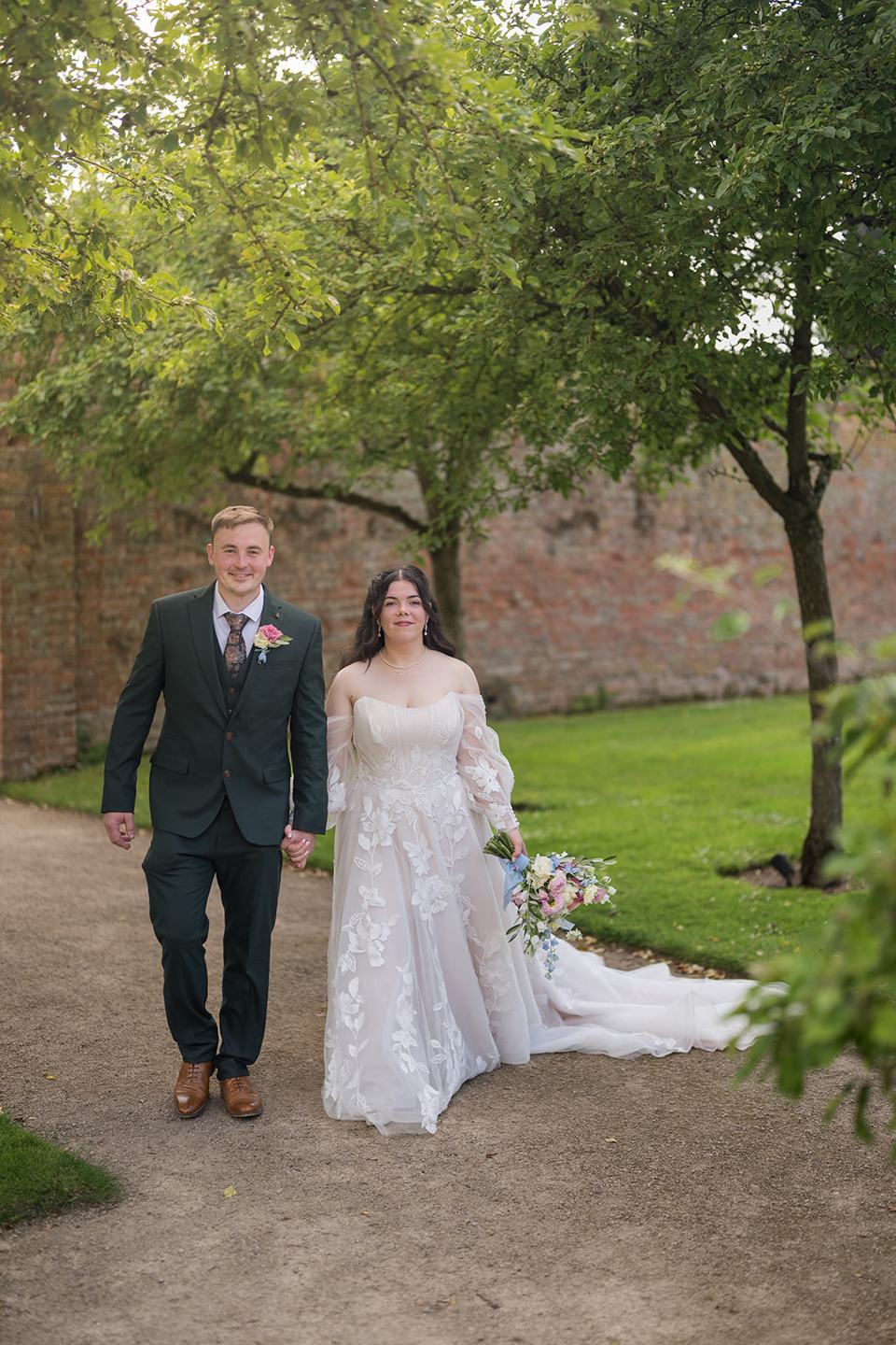 Couple walking through the gardens at Abi and Ben’s Combermere Abbey wedding