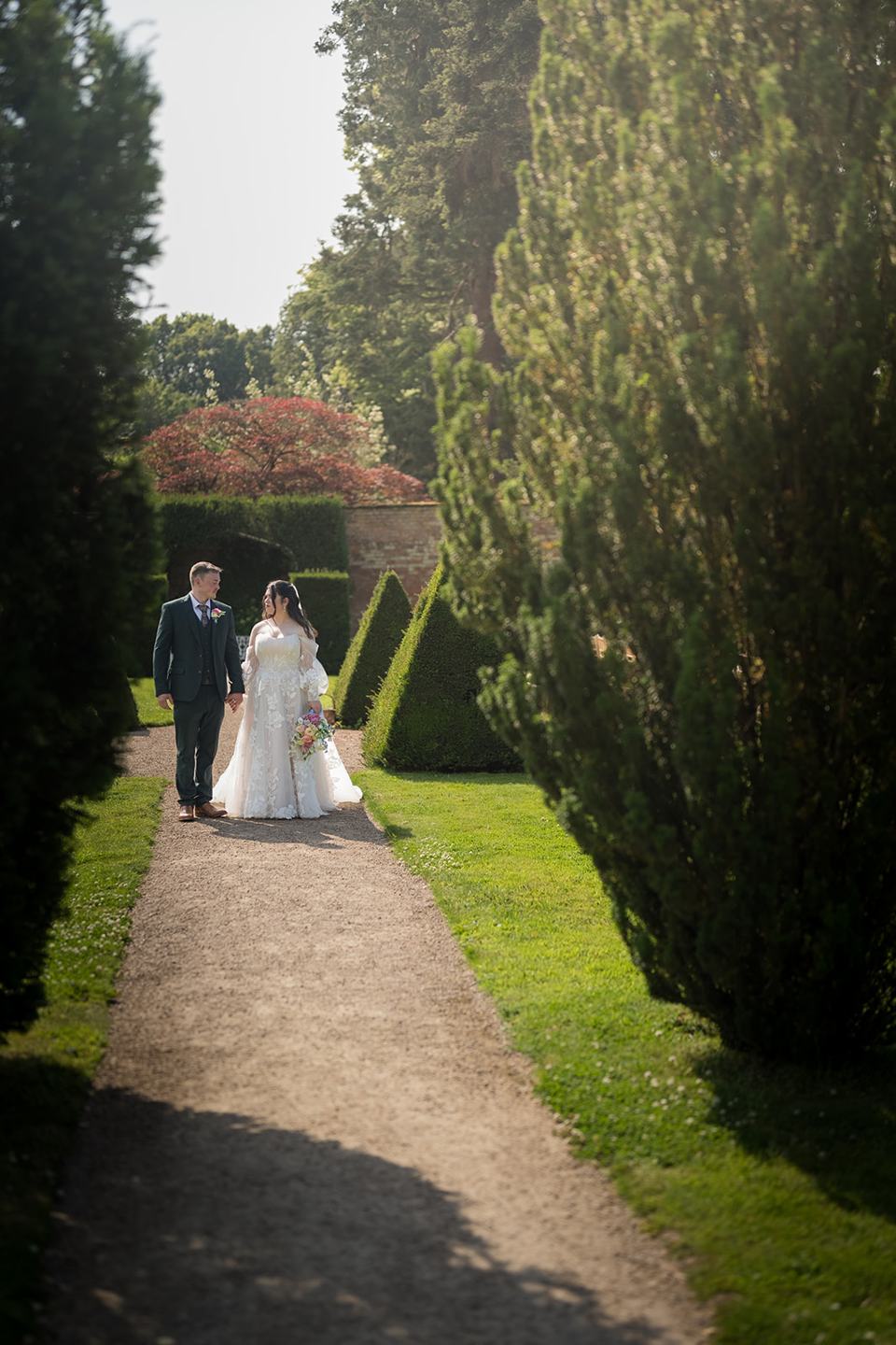 Couple framed by the clipped hedges at Abi and Ben’s Combermere Abbey wedding
