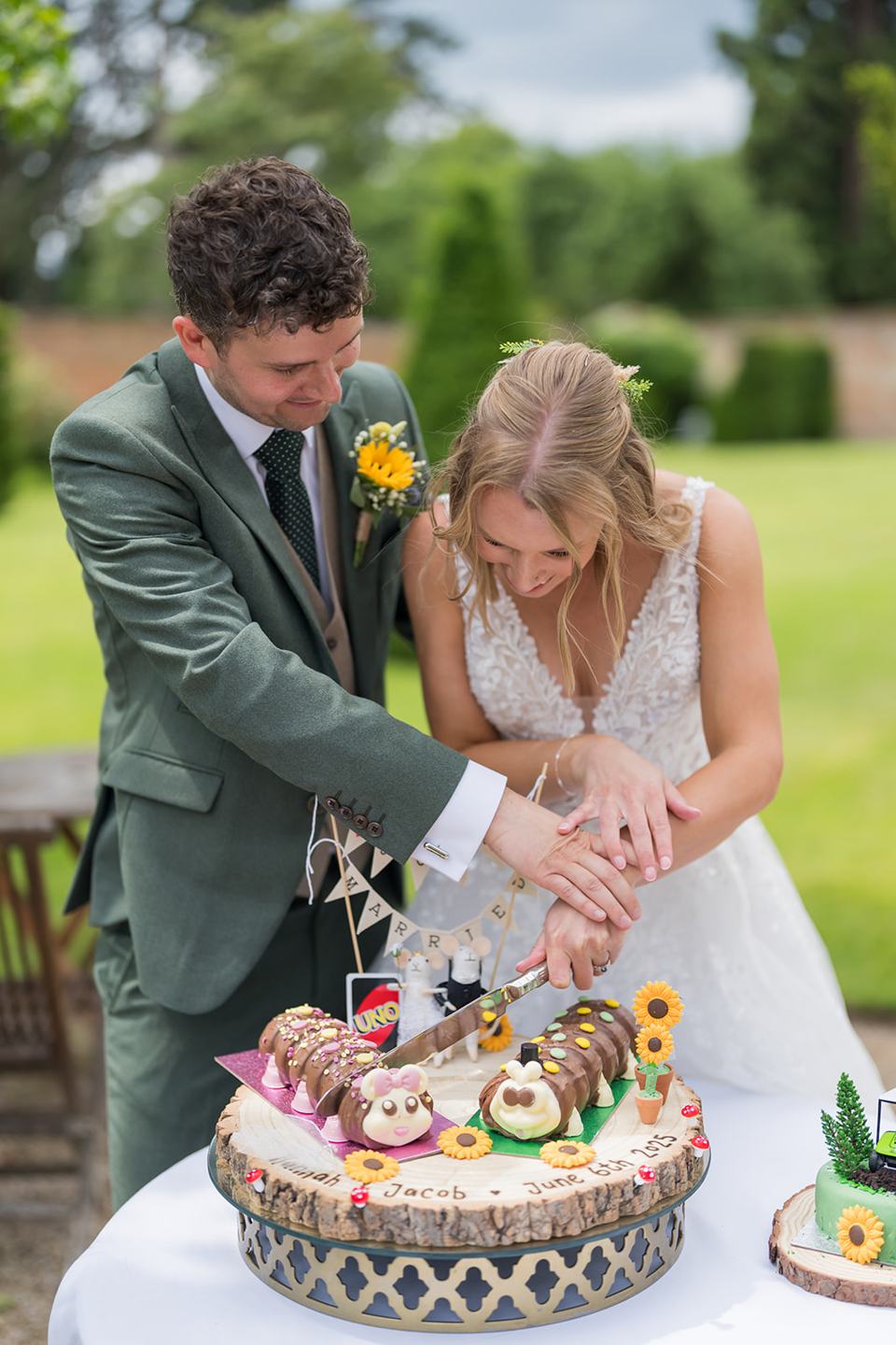 Cutting the wedding cake outdoors at Hannah and Jacob’s Combermere Abbey wedding