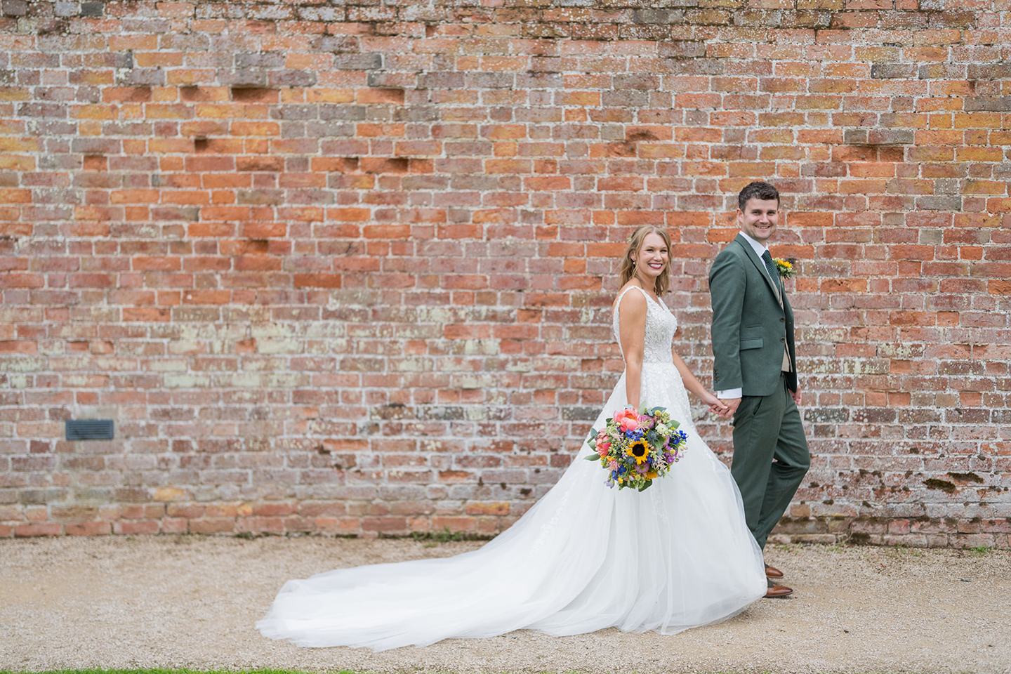 Newlyweds beside the brick wall at Hannah and Jacob’s Combermere Abbey wedding