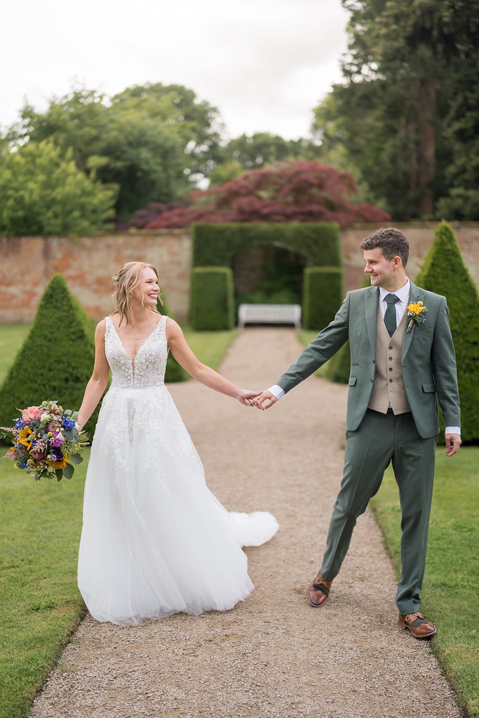 Couple walking between the hedges at Hannah and Jacob’s Combermere Abbey wedding