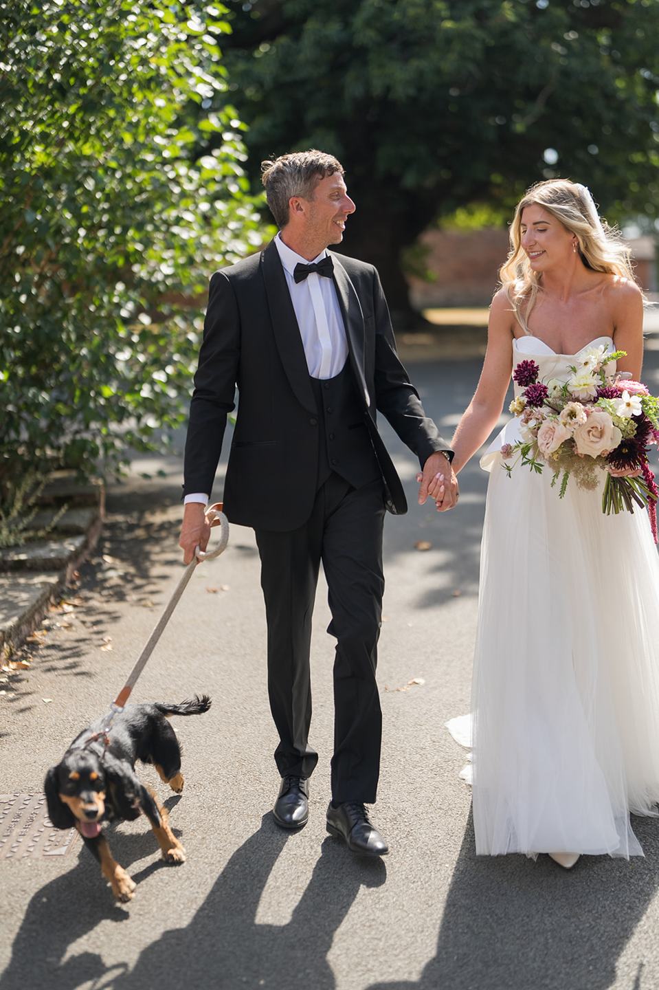 Newlyweds walking with their dog at Lauren and Tom’s Dorfold Hall wedding