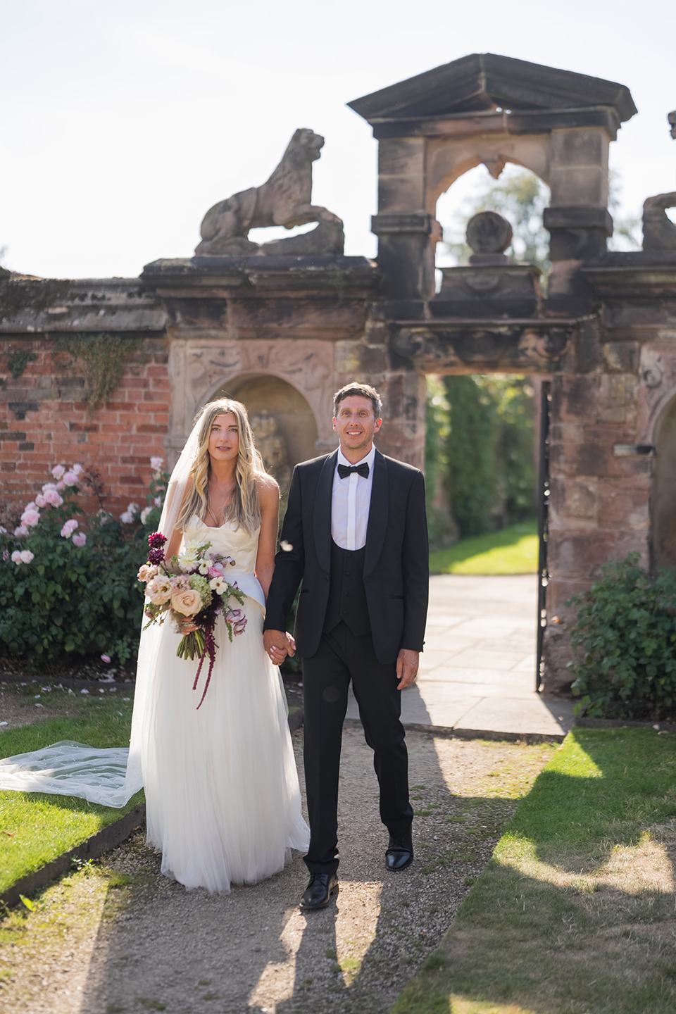 Newlyweds beside the garden gateway at Lauren and Tom’s Dorfold Hall wedding