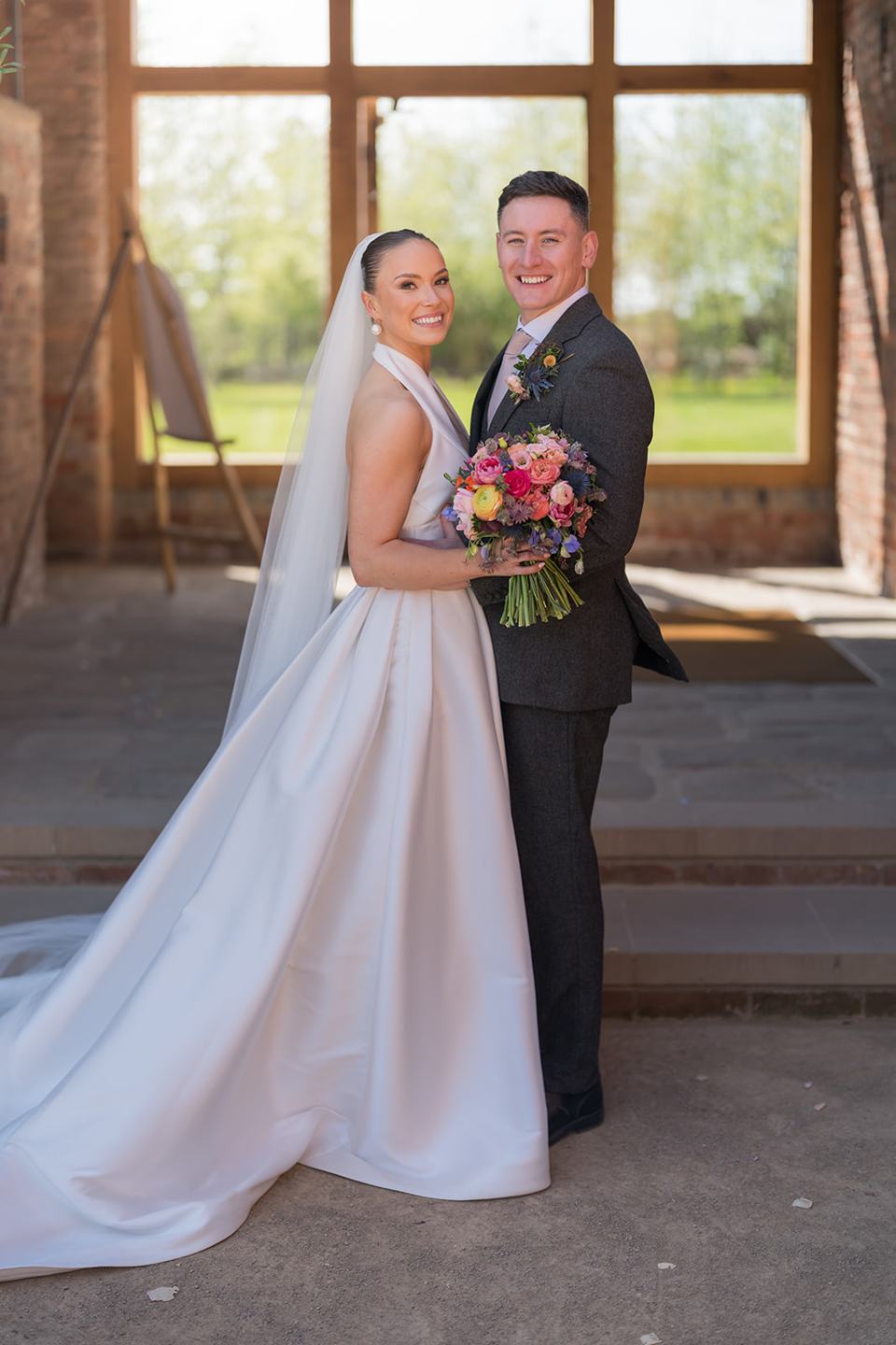 Couple portrait beside the barn window at Georgie and Matt’s Grangefields wedding