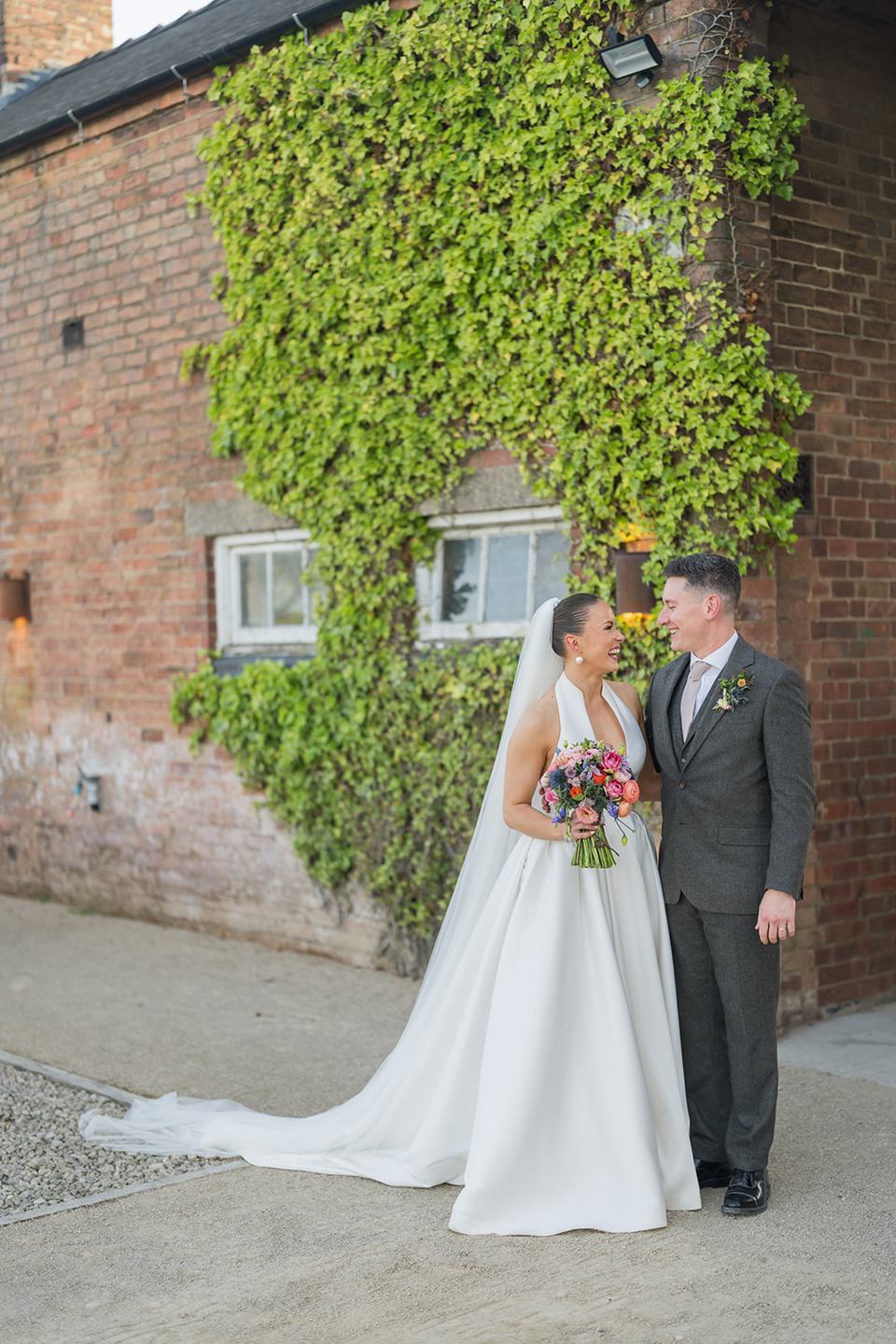 Couple beside the ivy-covered brickwork at Georgie and Matt’s Grangefields wedding