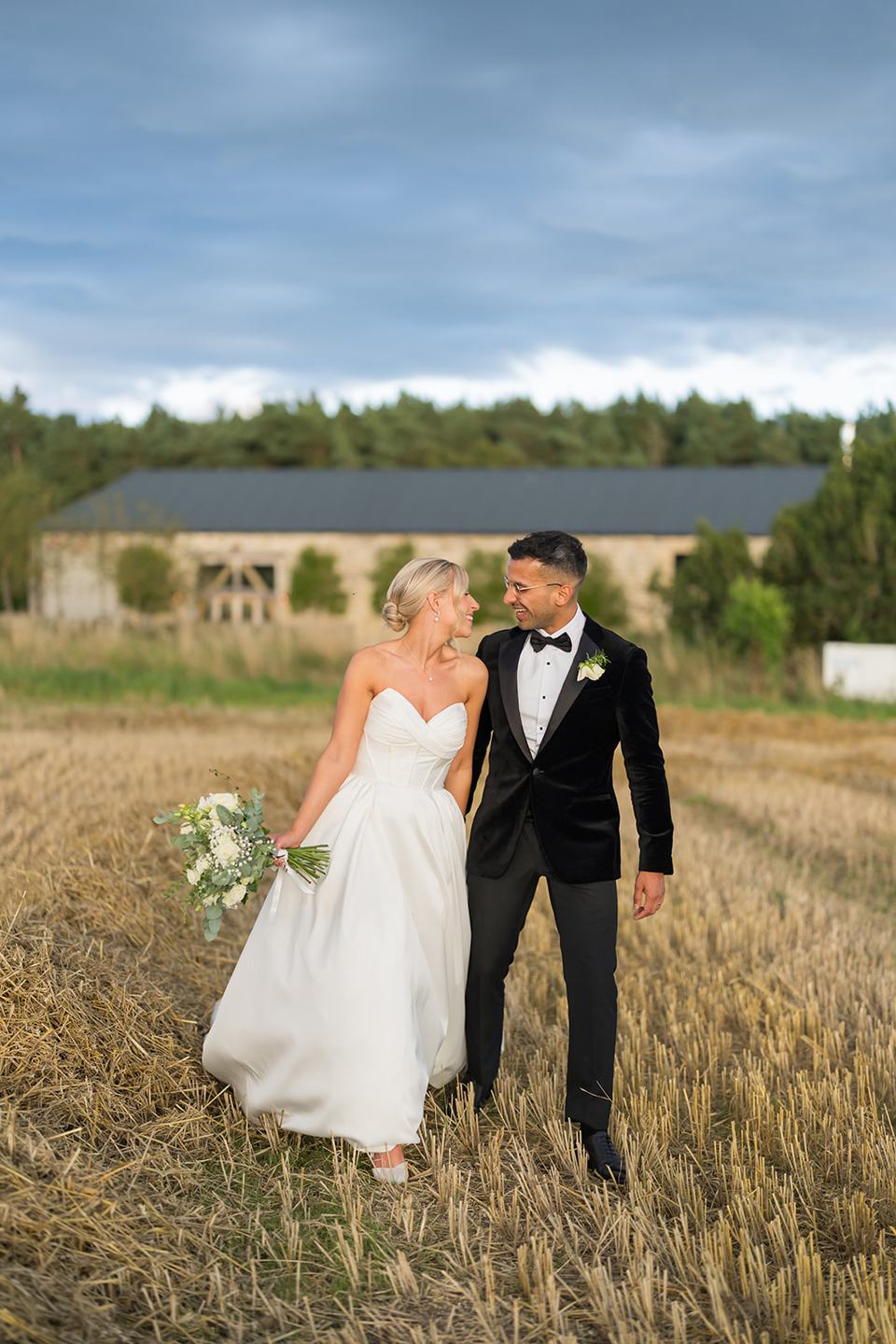 Newlyweds in the meadow with the barn behind at Mia and Herman’s Healey Barn wedding