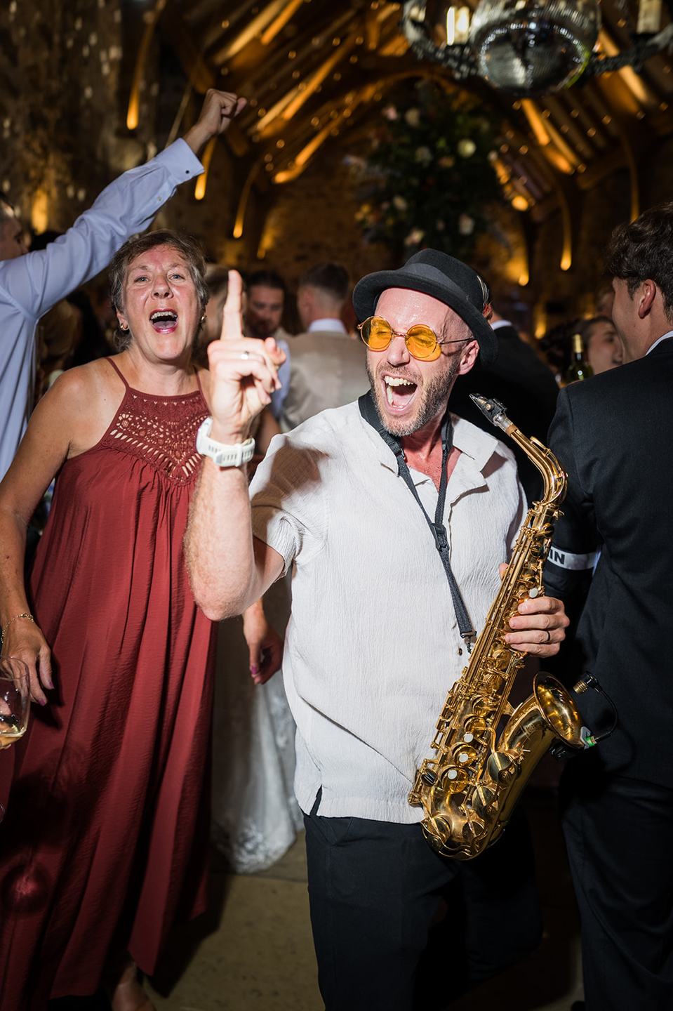 Guests celebrating with the saxophonist at Sophie and Sam’s Healey Barn wedding