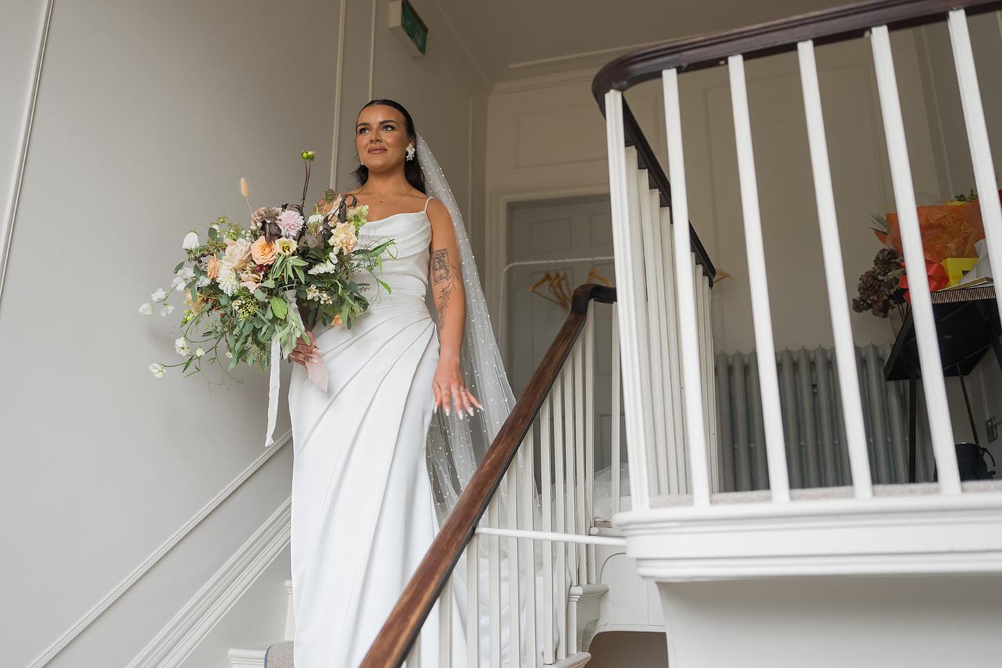 Bride descending the staircase at Sally and Callum’s Hornington Manor wedding
