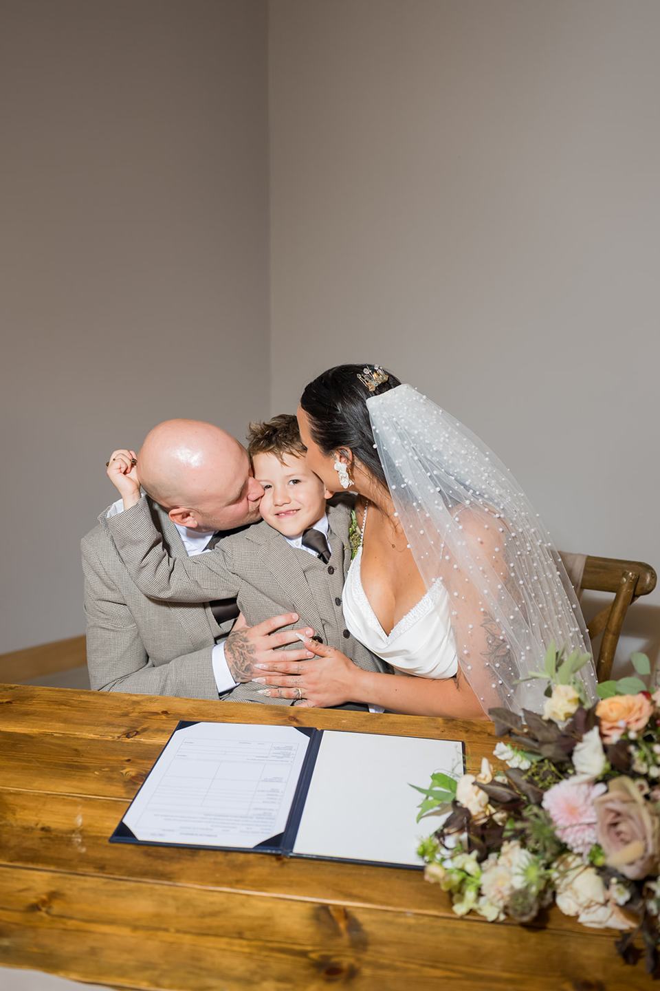 Signing the register with their child at Sally and Callum’s Hornington Manor wedding