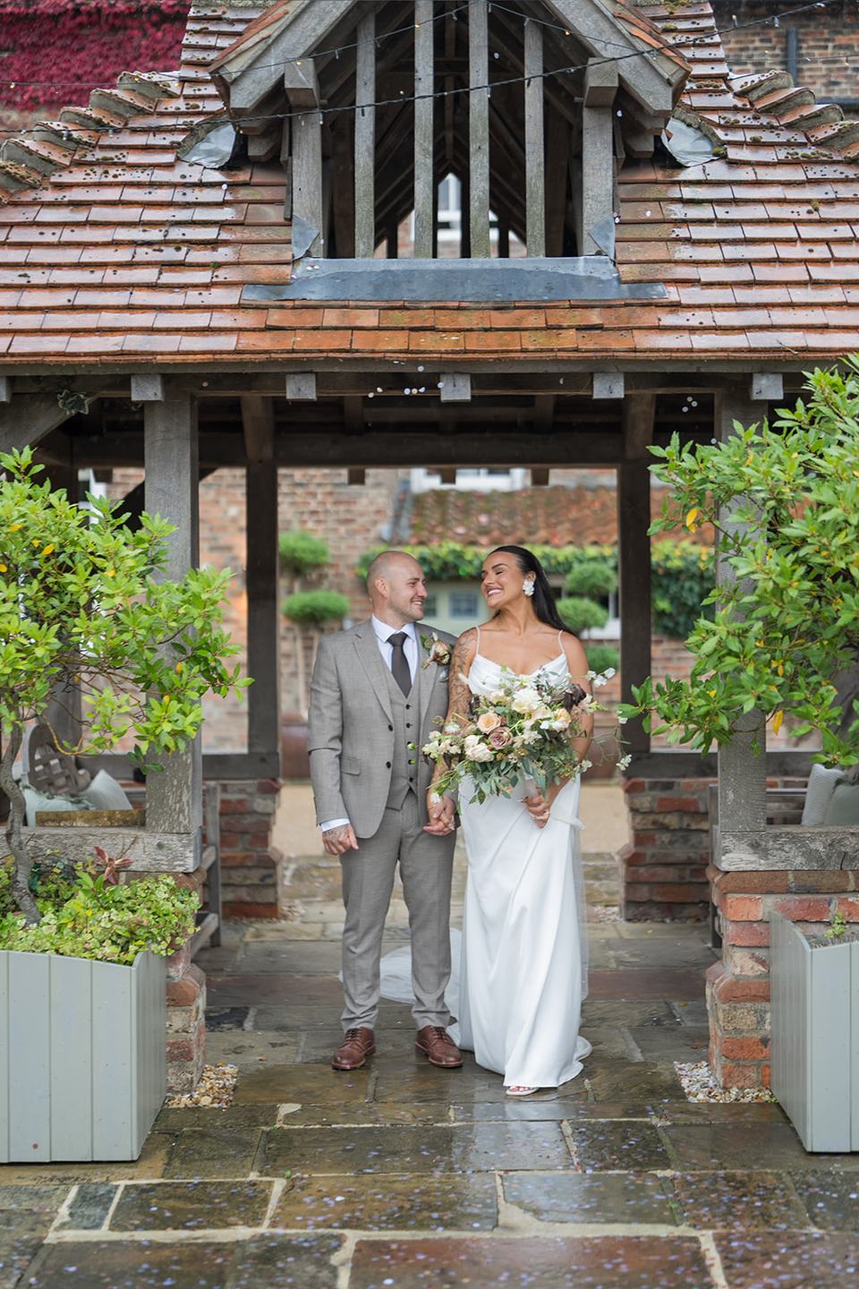 Couple beneath the covered gateway at Sally and Callum’s Hornington Manor wedding