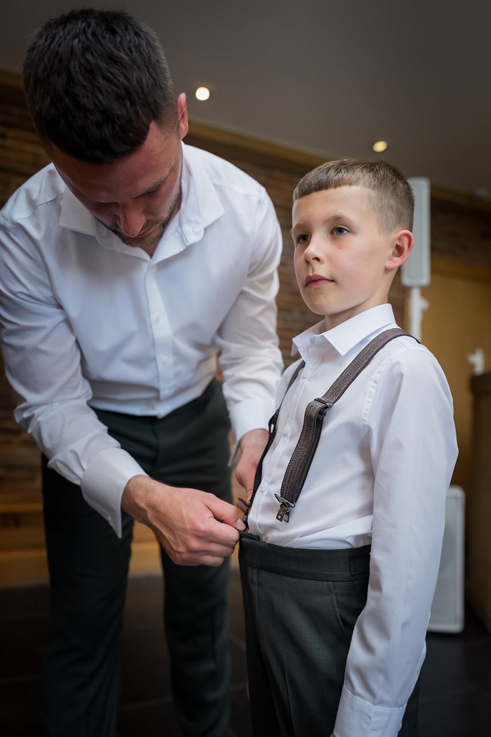Groom helping a young guest get ready at Kate and Kieran’s Mythe Barn wedding