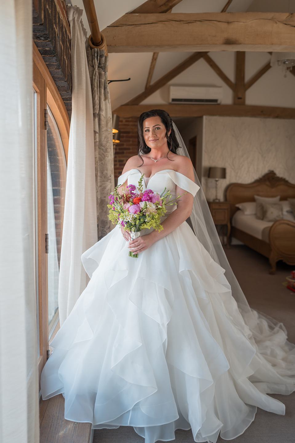 Bride beside the window at Kate and Kieran’s Mythe Barn wedding