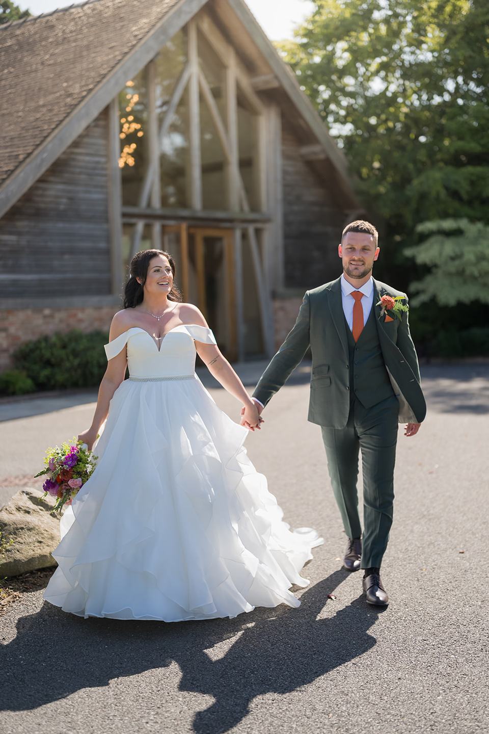 Newlyweds walking outside at Kate and Kieran’s Mythe Barn wedding