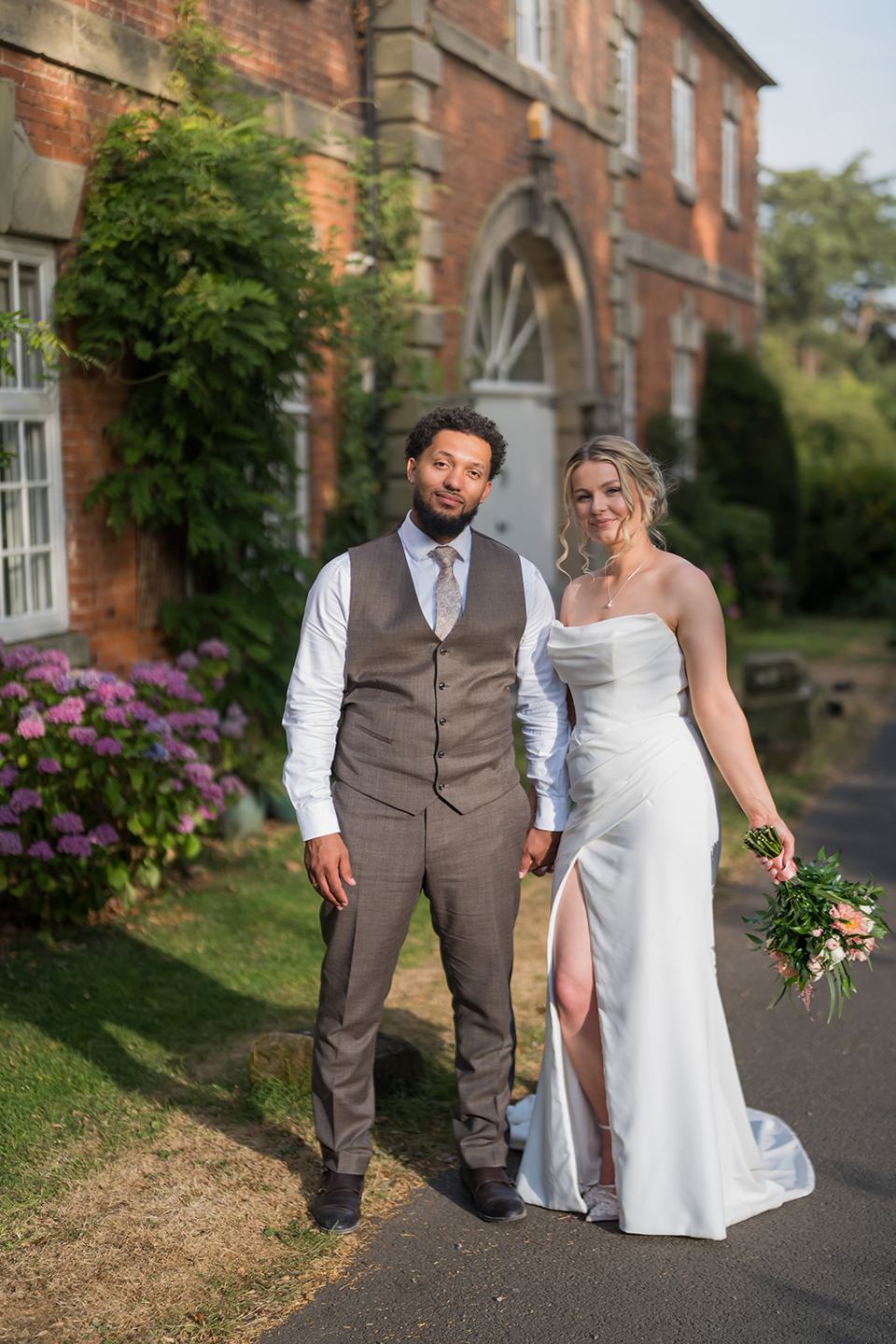 Couple beside the brick buildings at Kate and Jacob’s The Orangery at Ingestre wedding